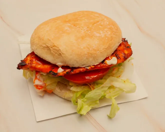 A chicken burger with lettuce, tomato and mayo in a soft bun