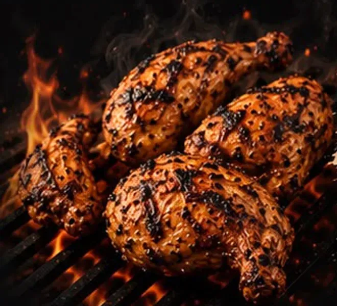 Four peri peri chicken halves charring over open flame on the grill