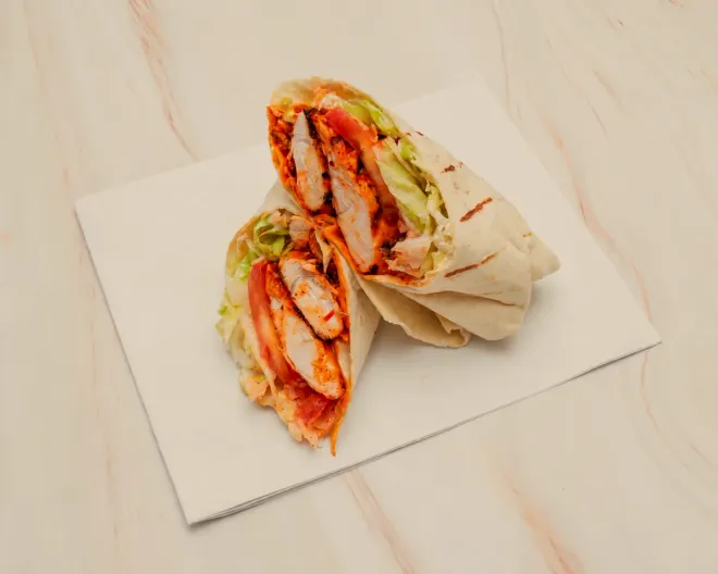 A chicken wrap cut in half, showing grilled chicken, lettuce and tomato