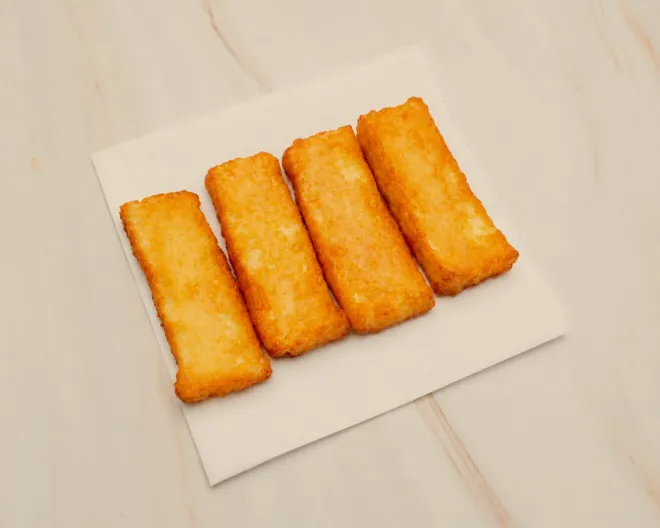 Four thick golden halloumi fries on a paper napkin
