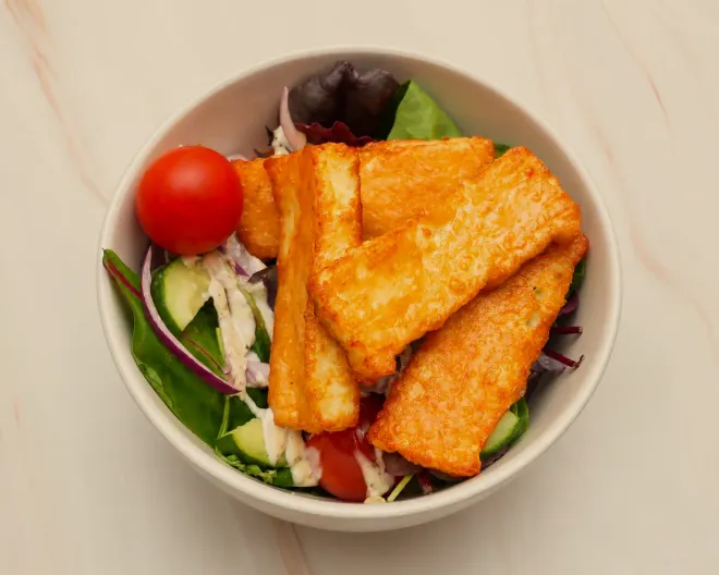 A halloumi salad box: grilled halloumi over leaves, cucumber and red onion