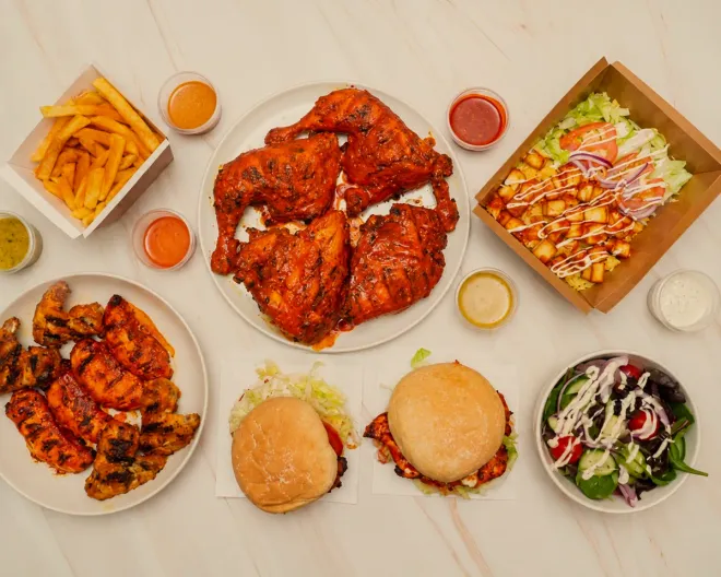 A full spread: whole chicken, wings, burgers, a salad box, chips and sauces