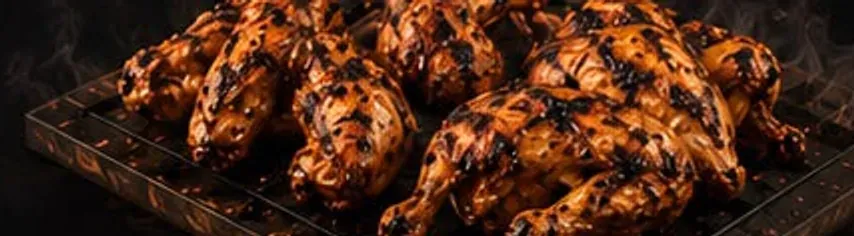 A rack of peri peri wings coming off the grill, skin blistered and charred